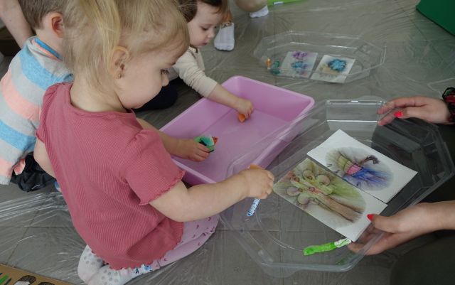 dzieci z pomocą rodziców malują farbkami na wodzie