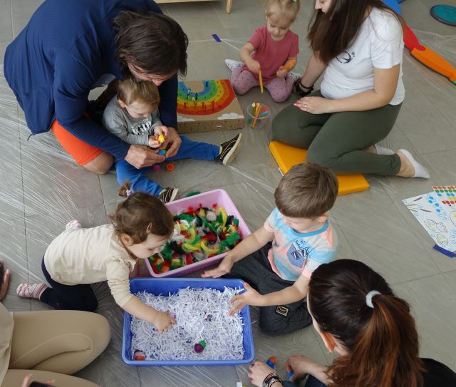 dzieci wyławiają jajeczka ukryte w kolorowych piórkach i w pociętym papierze