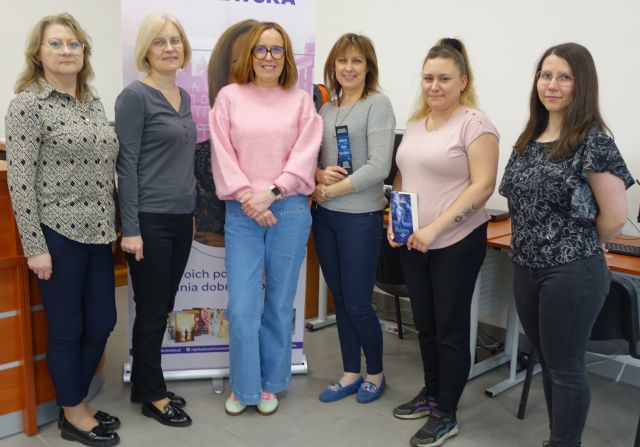 6 kobiet pozuje do zdjęcia - 5 bibliotekarek i autorka w różowym sweterku, w tle baner ze zdjęciem autorki