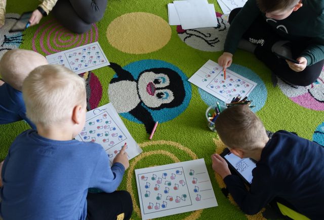 dzieci na dywanie rozkodowują obrazki