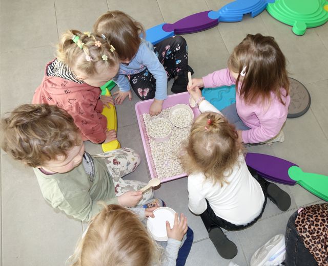 dzieci bawią się fasolą wsypaną do miski