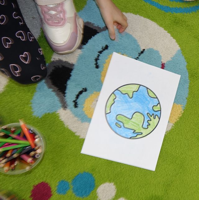 pokolorowana na kartce planeta ziemia leżąca na dywanie