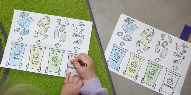 kartki z rysunkami ś mieci i koszy oraz dłonie dziecka z kredką