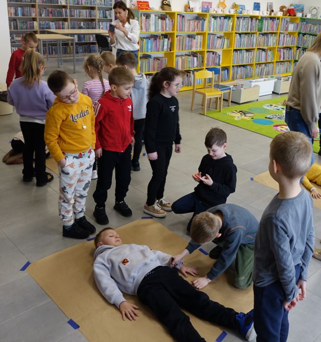 dzieci rysują na szarym papierze leżącym na dywanie