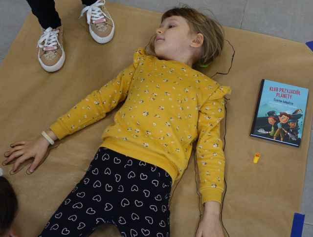 dziewczynka leżąca na szarym arkuszu papieru