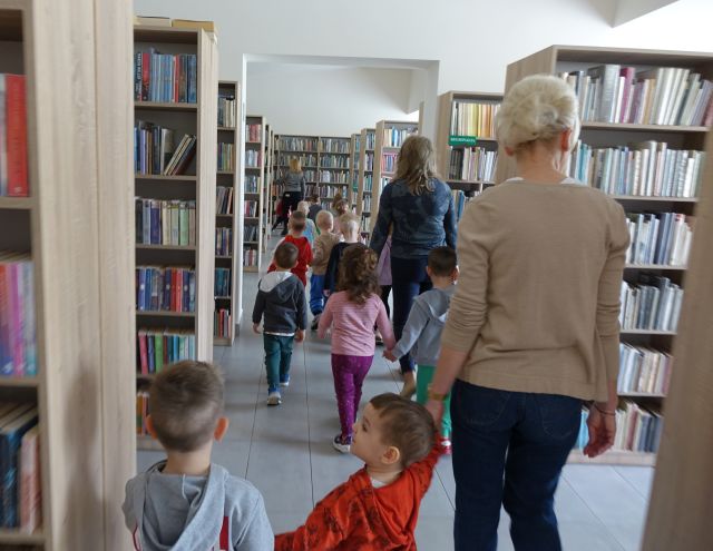 przedszkolaki spacerują pomiędzy regałami z książkami