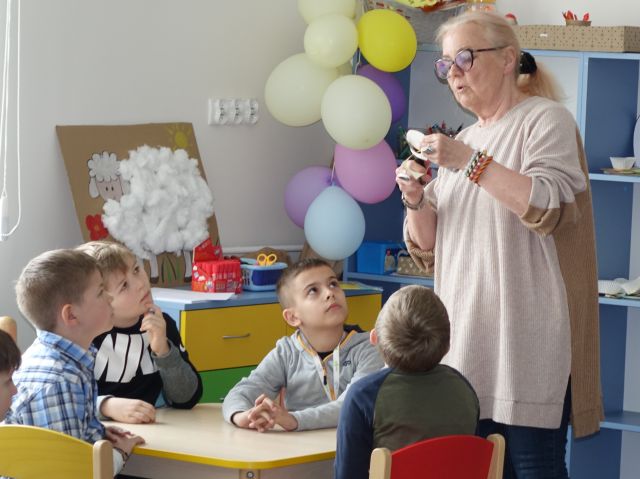 kobieta pokazuje dzieciom jak wycinać figury geometryczne z wycinanek