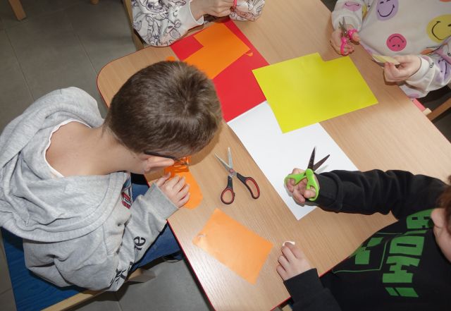 dzieci wycinają z kolorowych wycinanek kwadraty