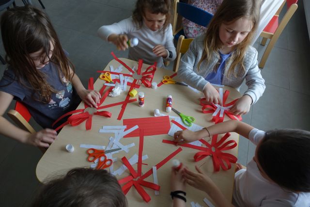 dzieci robią kotyliony z białych i czerwonych pasków