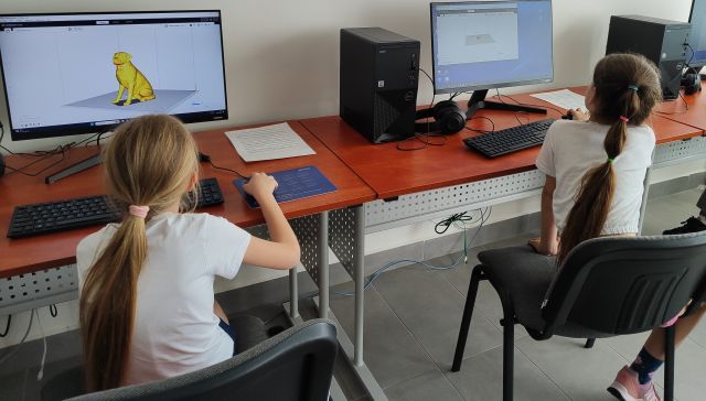 dwie dziewczynki siedzą przed komputerami