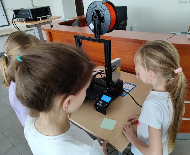 trzy dziewczynki patrzą na drukarkę 3D
