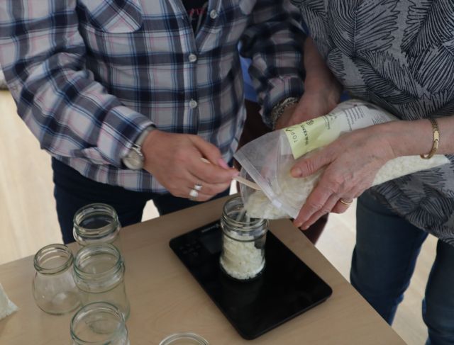 dłonie dwóch kobiet wsypujących do słoiczków soję