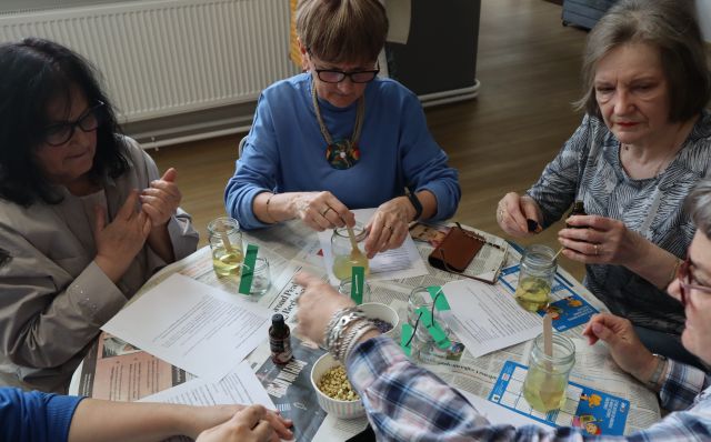 kobiety siedzące przy stołach robią świece sojowe w słoiczkach