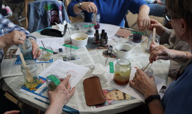 kobiety siedzące przy stołach robią świece sojowe w słoiczkach