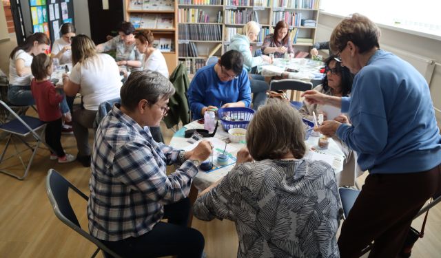 kobiety siedzące przy stołach robią świece sojowe w słoiczkach