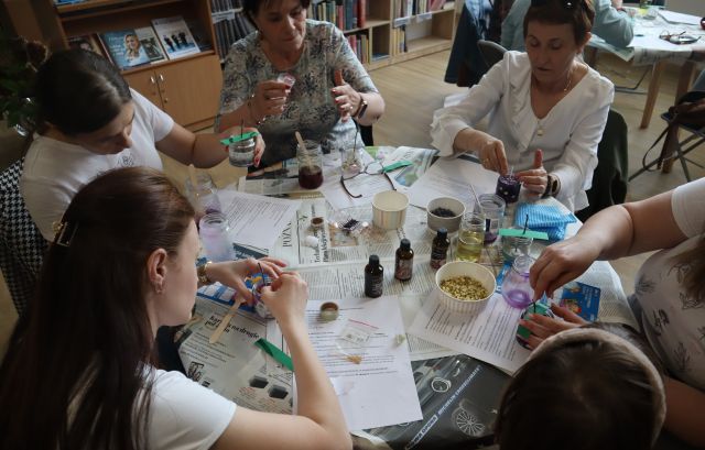 kobiety siedzące przy stołach robią świece sojowe w słoiczkach