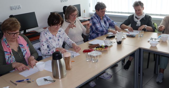 seniorki ćwiczą dłońmi siedząc przy stołach