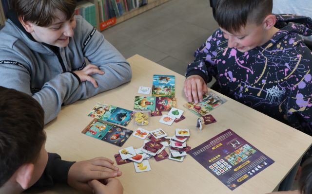 młodzież przy stoliku gra w grę planszową