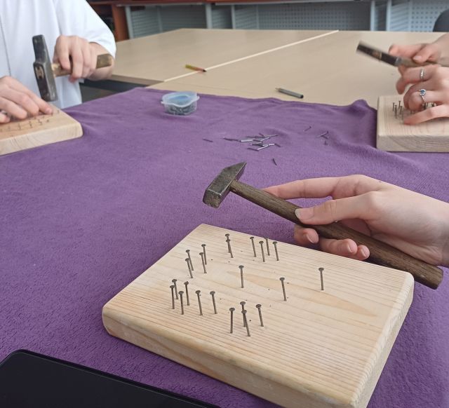 ręka z młodkiem, obok deseczka z gwóźdźmi