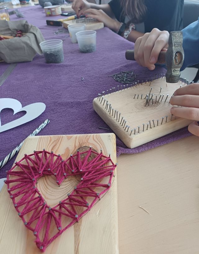 ręce wbijające gwoździe w deseczkę