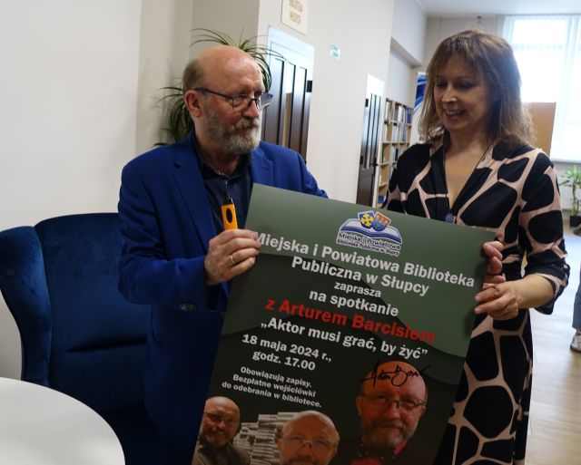 aktor i dyrektorka biblioteki trzymający w rękach plakat z zaproszeniem na spotkanie