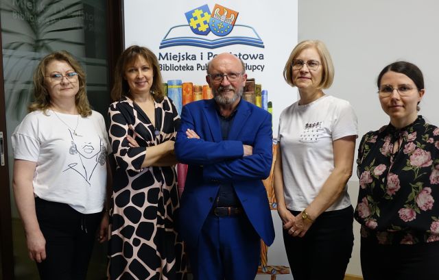 4 kobiety i aktor pozujący do zdjęcia, w tle baner z logo i nazwą biblioteki