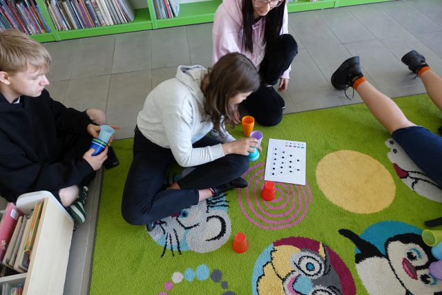 młodzież układa kolorowe kubeczki według zakodowanego rysunku