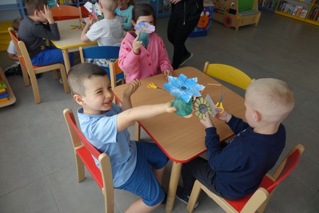 dzieci pokazują pokolowane przez sioebie kwiatki na kartkach