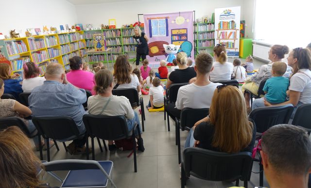 animatorka stoi przed dziećmi i rodzicami siedzącymi