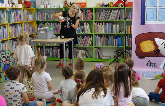 animatorka robi doświadczenia z cieczą a dzieci przyglądają się siedząc na podłodze