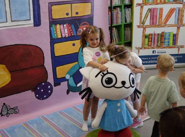 dwie dziewczynki przytulają się do dużej maskotki Kici Koci