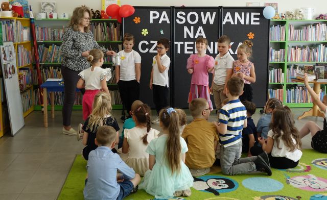 przedszkolaki stoją na środku sali przed siedzącymi dziećmi