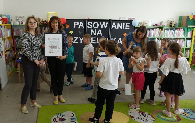 2 kobiety pokazują pamiątkowe podziękowa nia, obok nich stoją dzieci