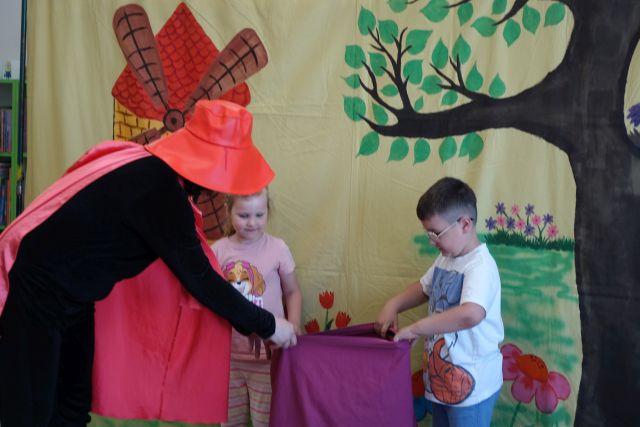 aktor przebrany za kota w butach trzyma z chłopcem i dziewczynką fioletowy worek