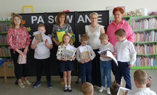bibliotekarka, dyrektorka biblioteki, przedszkolanka i dyrektorka przedszkola pozują do zdjęcia z 5 dziećmi