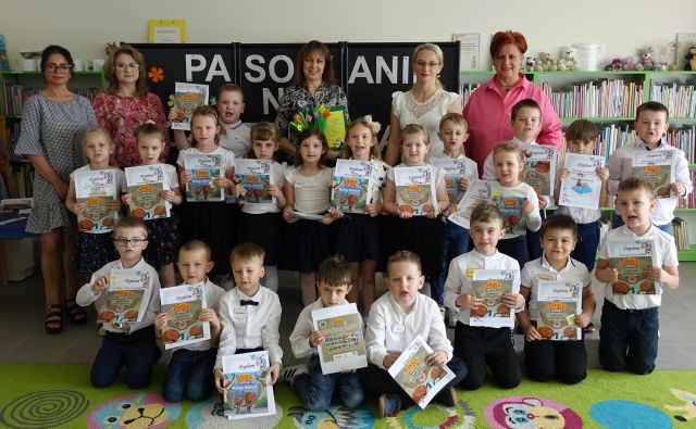 dzieci z dyplomami i książkami oraz 5 kobiet pozuje do zdjęcia