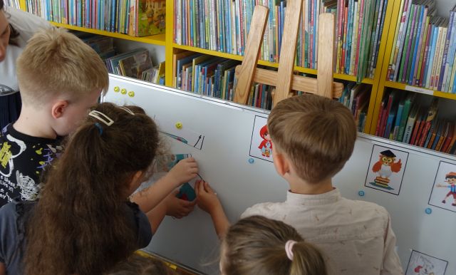 przedszkolaki przypinają do tablicy magnetycznej obrazki