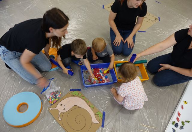 dzieci i mamy bawią się kolorowym ryżem i makaronem wsypanym do miski
