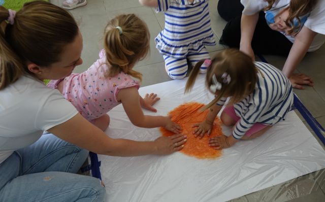 dzieci z mamami rozmazują farbę pod folią