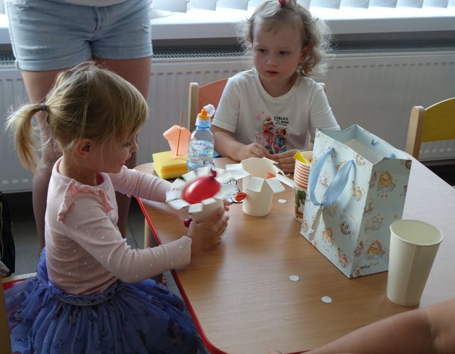 małę dzieci z mamami kolorują papierowe kubeczki