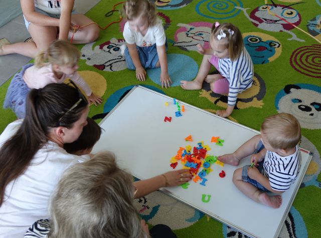 dzieci przyklejają literki do tablicy magnetycznej