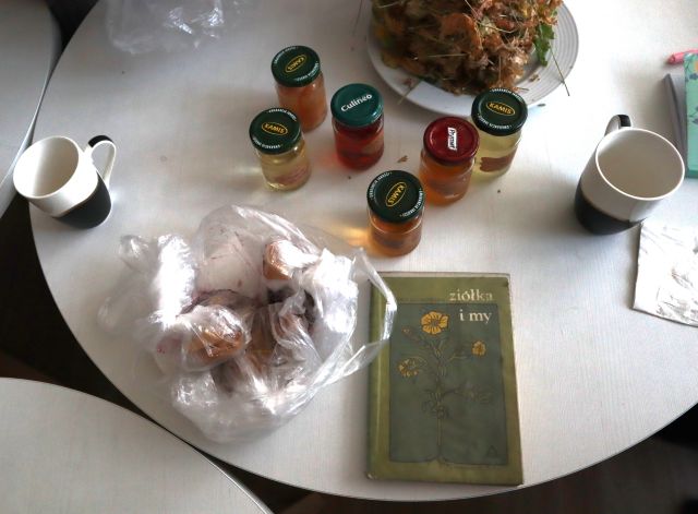 na stole stoją syropy i octy w słoiczkach oraz książka o ziołach