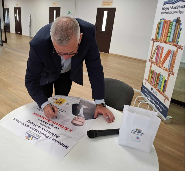 mężczyzna podpisujący się na plakacie