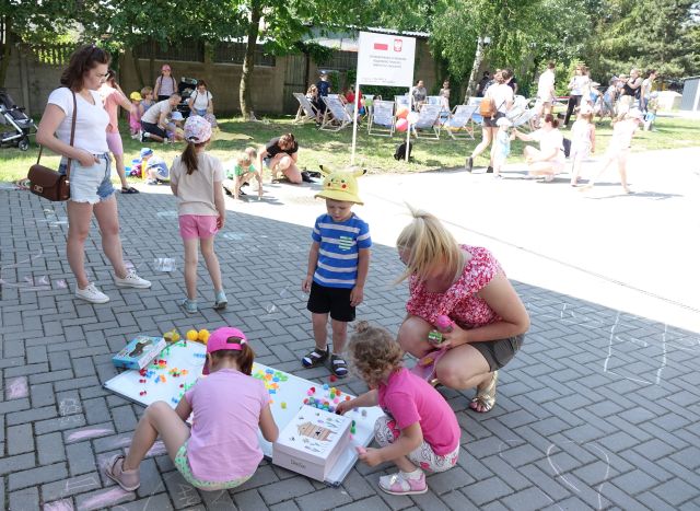 dzieci i rodzice przyklejają do tablicy magnetycznej kolorowe piłeczki