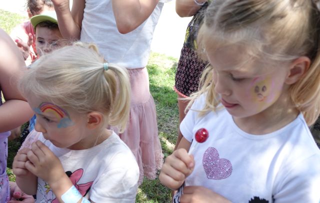 dwie dziewczynki z rysunkami na twarzach i lizakami