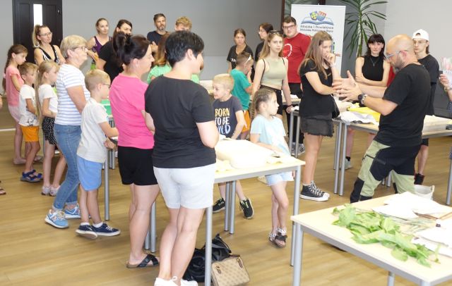 uczestnicy warsztatów stoją przy stołach