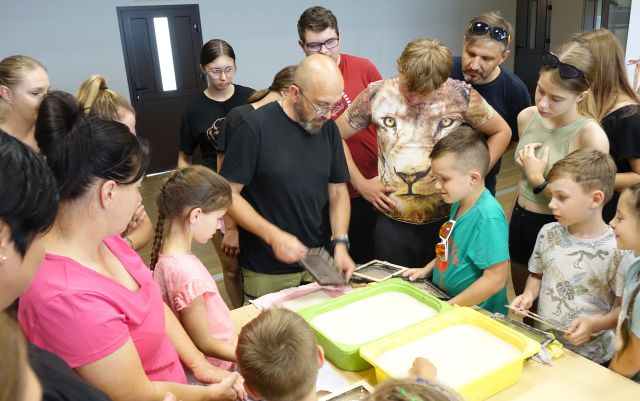 mężczyzna pokazuje uczestnikom warsztatów jak zrobić papier