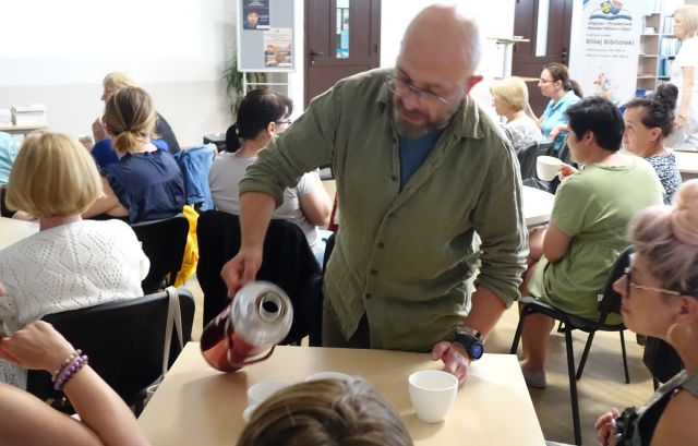 mężczyzzna nalewa z termosu herbatę uczestnikom warsztatów