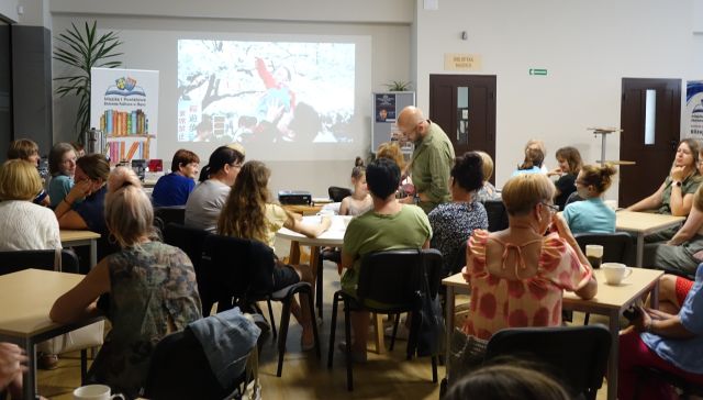 mężczyzna nalewa uczestnikom spotkania herbatę