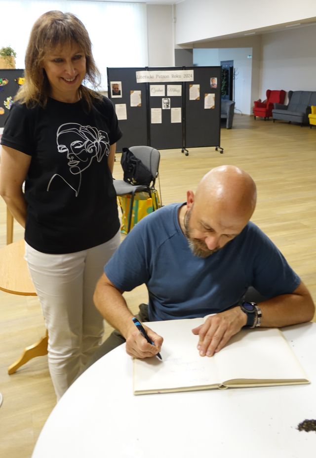 mężczyzna podpisuje dyrektorce biblioteki książkę